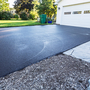 Asphalt driveway that leads up to a white garage door.